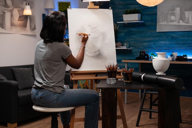 Étudiant peintre debout devant une toile dessinant une structure de vase artistique pour un cours d'art. Jeune artiste femme peignant un croquis à l'aide d'outils d'illustration professionnels. Concept de peintures de créativité