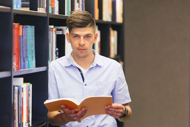 Étudiant en regardant la caméra en lisant un livre