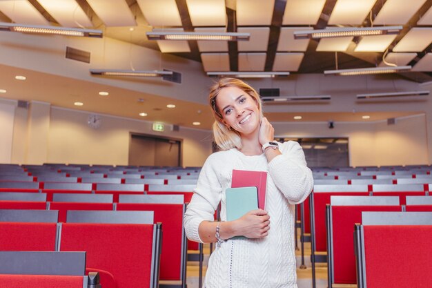 Étudiant souriant avec des cahiers dans le hall