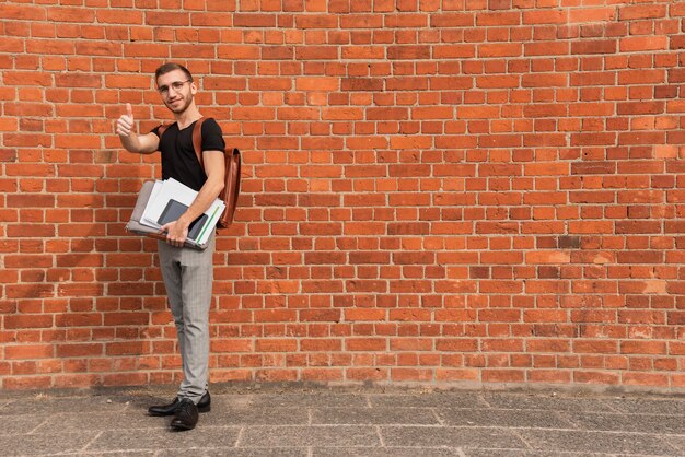 Étudiant universitaire, debout, devant, a, mur brique, copie, espace, fond