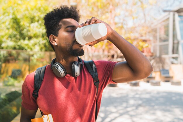 Étudiant à l'université afro buvant une tasse de café.