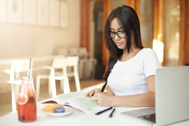 Étudiante asiatique à faire ses devoirs sur le campus. Fille de l'Est gaucher travaillant dans un café, futur avocat ou ingénieur.