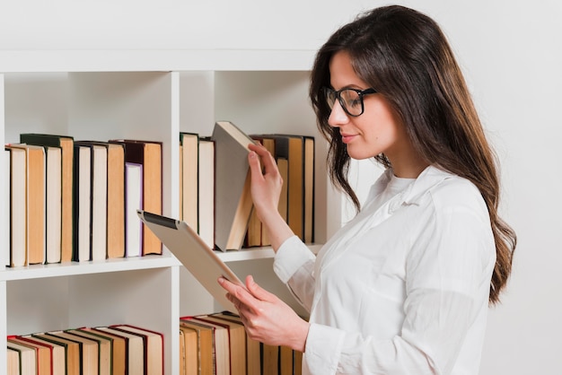 Étudiante dans une bibliothèque à l'aide de sa tablette numérique