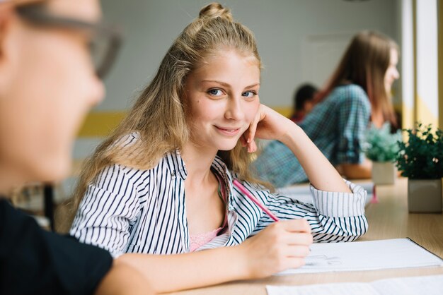 Étudiante étudiante adolescente écrivant et regardant la caméra