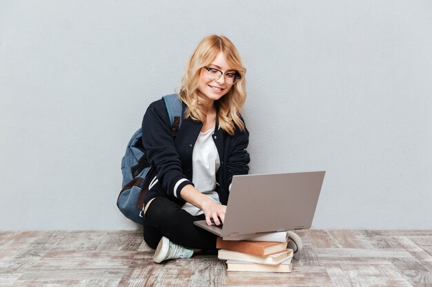 Étudiante gaie jeune femme à l'aide d'un ordinateur portable.