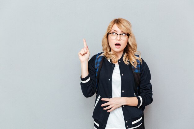 Étudiante jeune femme surprise pointant.