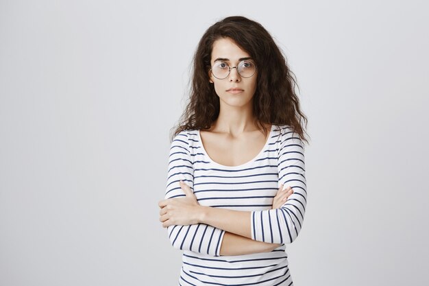 Étudiante sérieuse à lunettes ringard, poitrine croisée confiante