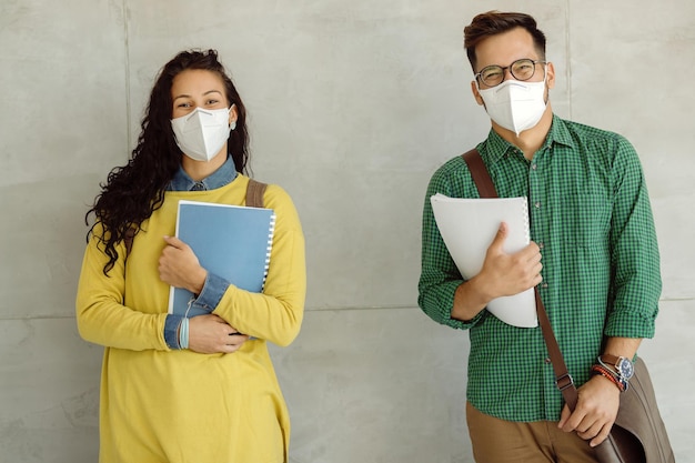 Étudiants heureux avec des masques protecteurs contre le mur à l'université