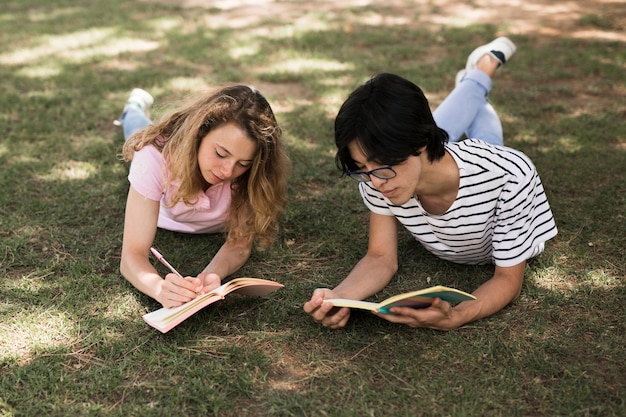 Étudiants multiethniques sur l&#39;herbe dans un parc avec des livres