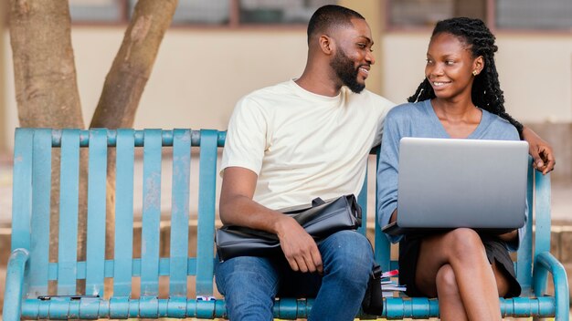 Étudiants de plan moyen assis sur un banc