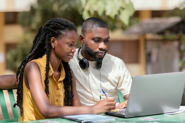 Étudiants de plan moyen travaillant avec un ordinateur portable