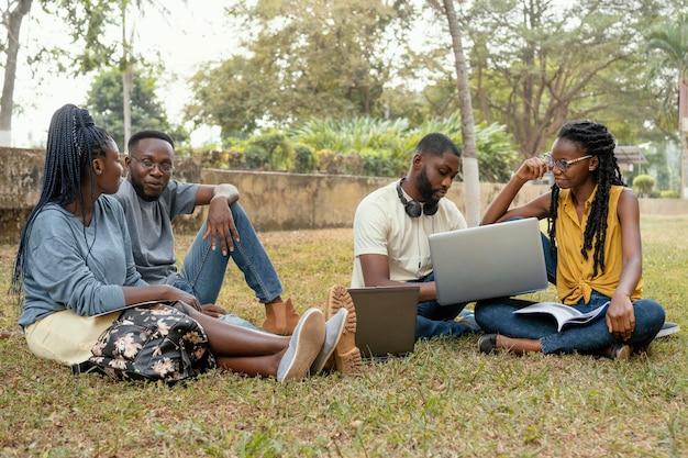 Étudiants de tir complet assis sur l'herbe