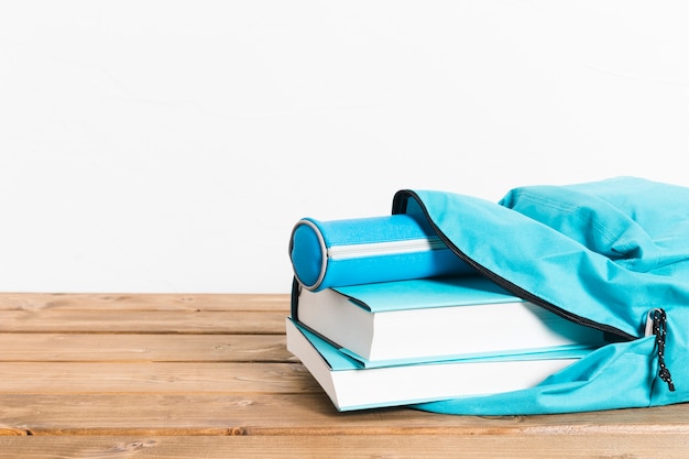 Étui à livres et crayons bleu en ouverture cartable sur table en bois