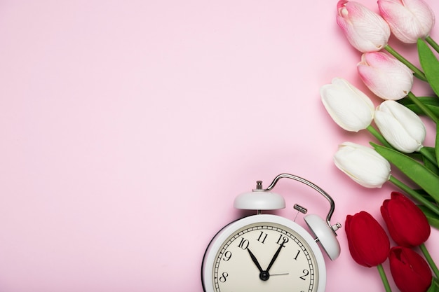 Tulipes blanches et rouges à côté de l'horloge avec copie-espace