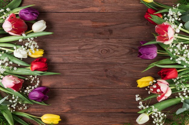 Tulipes colorées et fleur d&#39;haleine de bébé sur le côté d&#39;une surface texturée en bois