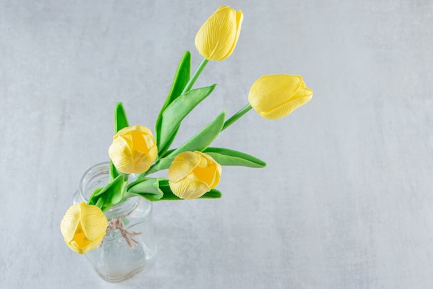 Tulipes jaunes dans un bocal, sur le tableau blanc.