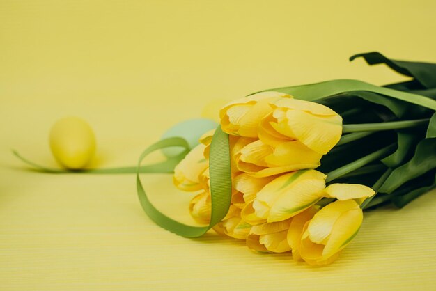 Tulipes jaunes et oeufs de pâques sur fond jaune