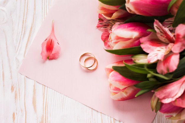 Photo gratuite tulipes sur table à côté des bagues de fiançailles