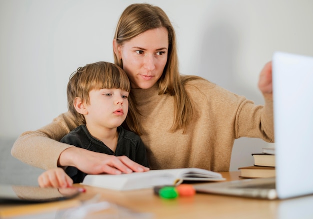 Tuteur femme enseignant enfant à la maison à l'aide d'un ordinateur portable