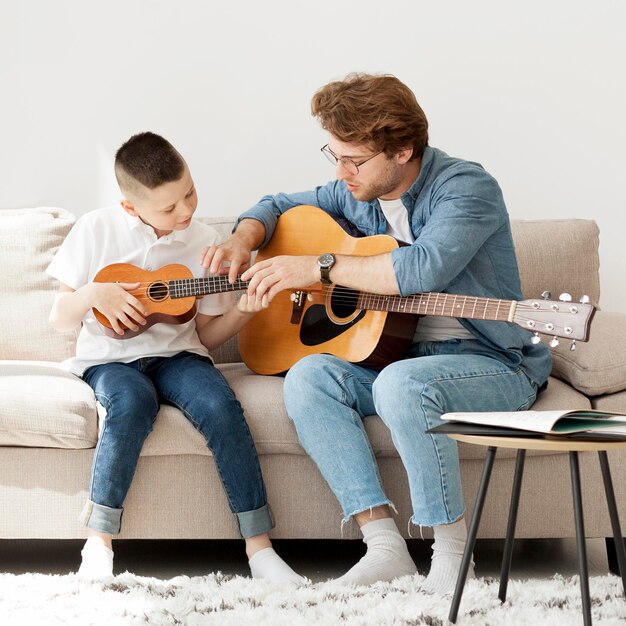 Tuteur et garçon apprenant la guitare acoustique et le ukulélé