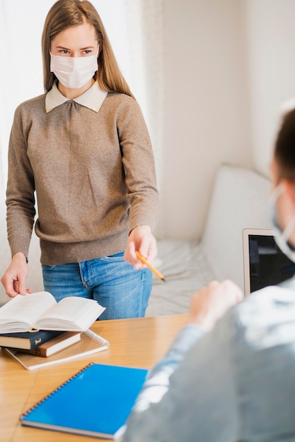 Tutrice avec masque médical enseignant étudiant masculin à la maison