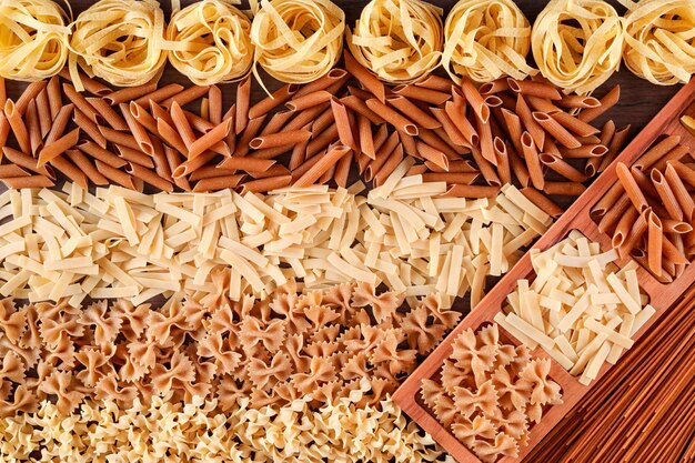 types de pâtes crues penne fusilli tagliatelles spaghetti vue de dessus