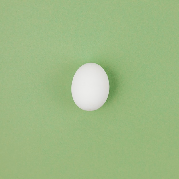 Œuf de poule blanche sur table verte