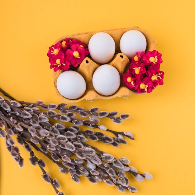 Œufs blancs dans une grille avec des branches de saule sur la table