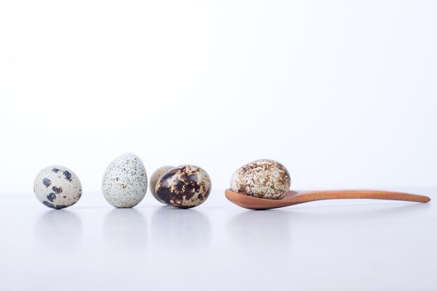 Œufs de caille bio sur une surface blanche avec une cuillère.