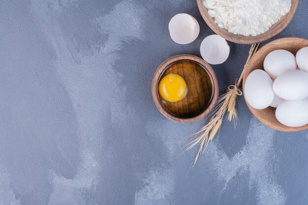 Œufs, coquilles d'œufs et jaune d'œuf dans une tasse en bois