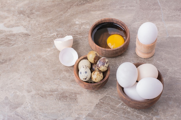 Œufs, coquilles d'œufs et jaune d'œuf dans une tasse en bois