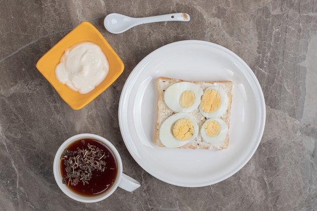 Œufs durs avec du pain sur une assiette et une tasse de thé. Photo de haute qualité