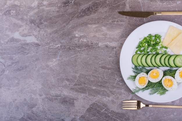 Œufs durs avec salade verte dans une assiette blanche.