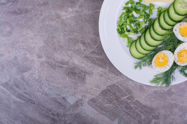 Œufs durs avec salade verte dans une assiette blanche.