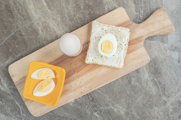 Œufs durs et tranches de pain grillé sur une planche à découper. Photo de haute qualité