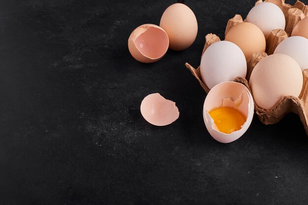 Œufs entiers et coquilles d'œufs dans un plateau en carton, vue du dessus.