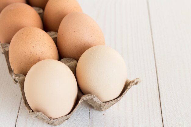 Œufs frais en carton sur bois blanc