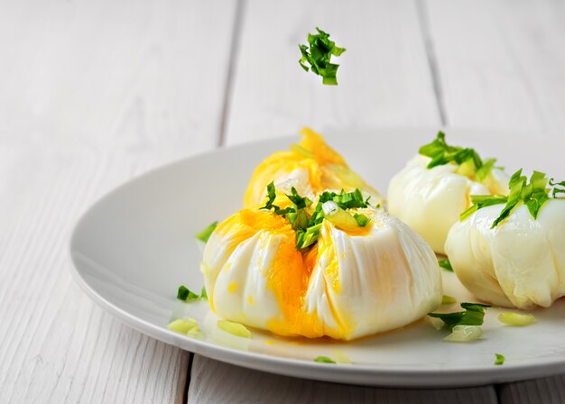 Œufs pochés décorés d'herbes fraîches sur une assiette blanche