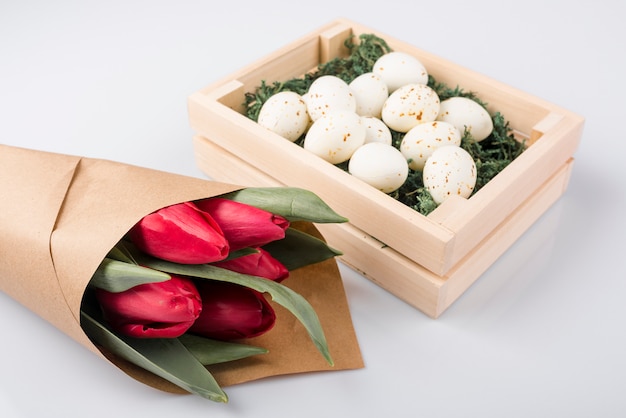 Œufs de poule blanche en boîte avec bouquet de tulipes