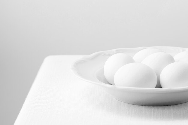 Œufs de poule blancs à angle élevé sur assiette