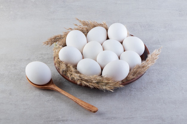 Œufs de poule blancs frais crus placés sur une surface en pierre.