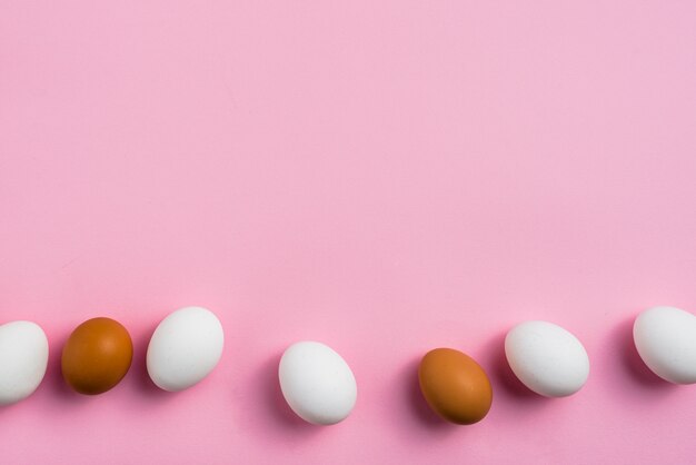 Œufs de poule dispersés sur une table rose