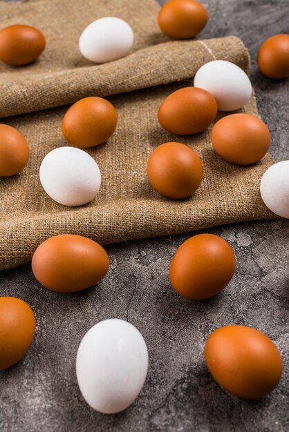 Œufs de poule dispersés sur une toile sur une table grise