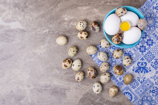 Œufs de poulet et de caille dans une tasse bleue.