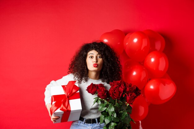 Vacances et célébration jolie femme célébrant l'anniversaire soufflant un baiser d'air recevoir des cadeaux et des fleurs...