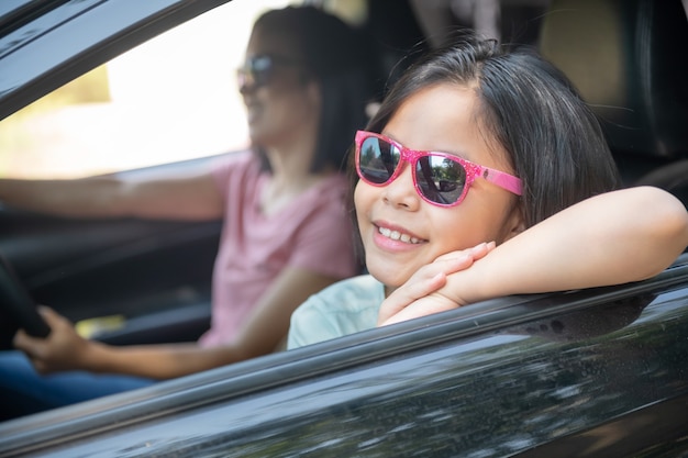 Vacances en famille, famille heureuse en voyage en voiture, maman conduisant une voiture pendant que sa fille est assise à côté, maman et fille voyagent. balade estivale en automobile.