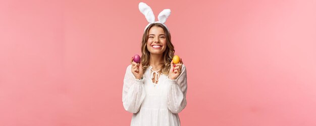 Vacances printemps et concept de fête Portrait d'une jolie fille blonde joyeuse dans des oreilles de lapin tenant des œufs colorés célébrant Pâques en famille profitant de passer une journée traditionnelle avec des personnes proches