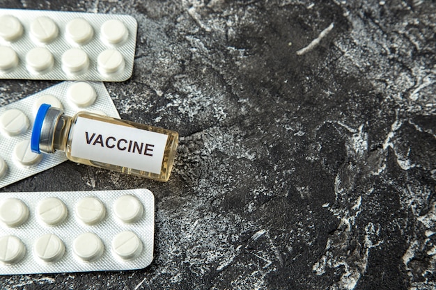 Vaccin antivirus vue de face avec des pilules sur fond gris clair isolement science de la santé covid- laboratoire de l'hôpital pandémique du virus