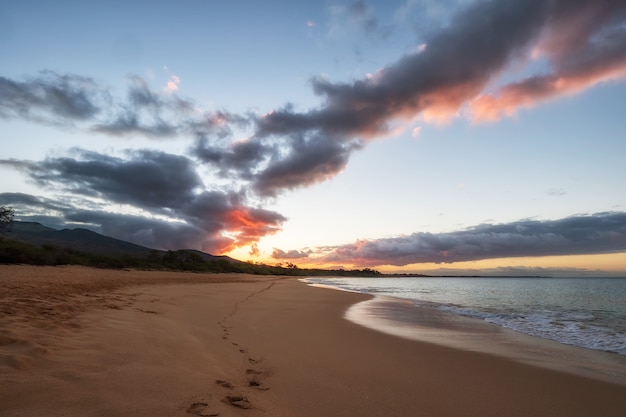 Photo gratuite vagues de la mer s'écrasant sur le rivage pendant le coucher du soleil