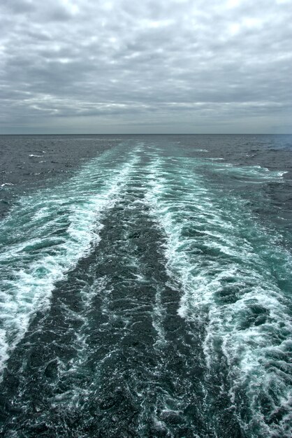 Vagues mousseuses à la surface de l'eau derrière le bateau de croisière